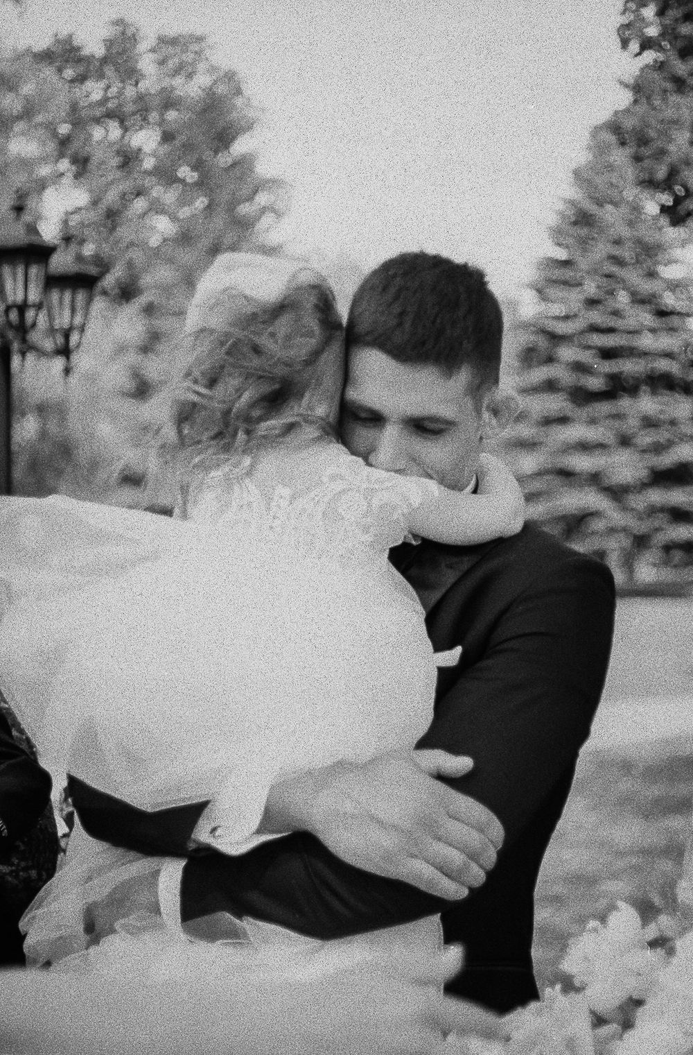 A black and white sequence showing romantic moments outdoors with evergreen trees in the background.