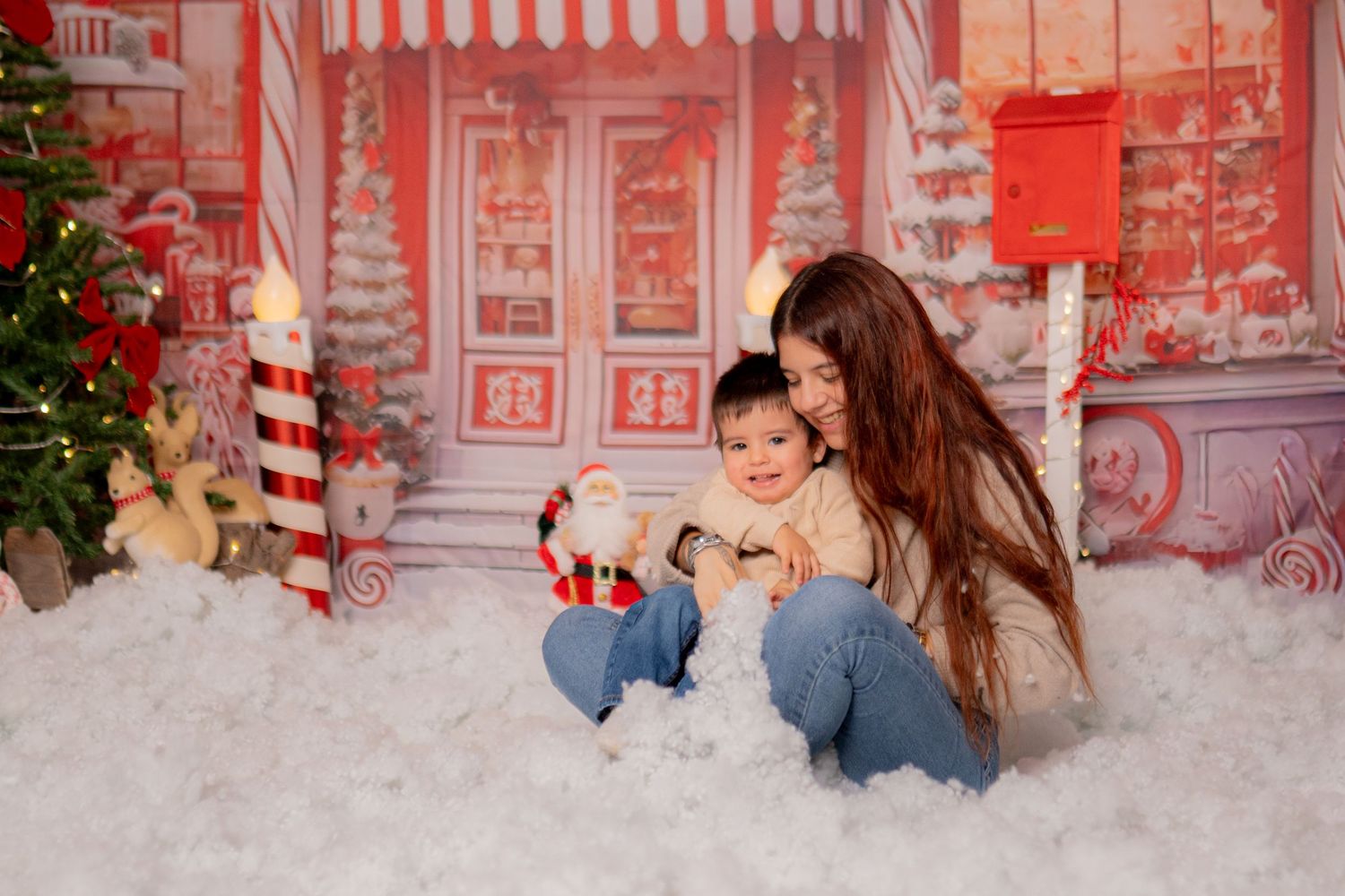 Christmas photo studio setup with red and white striped decorations and artificial snow.