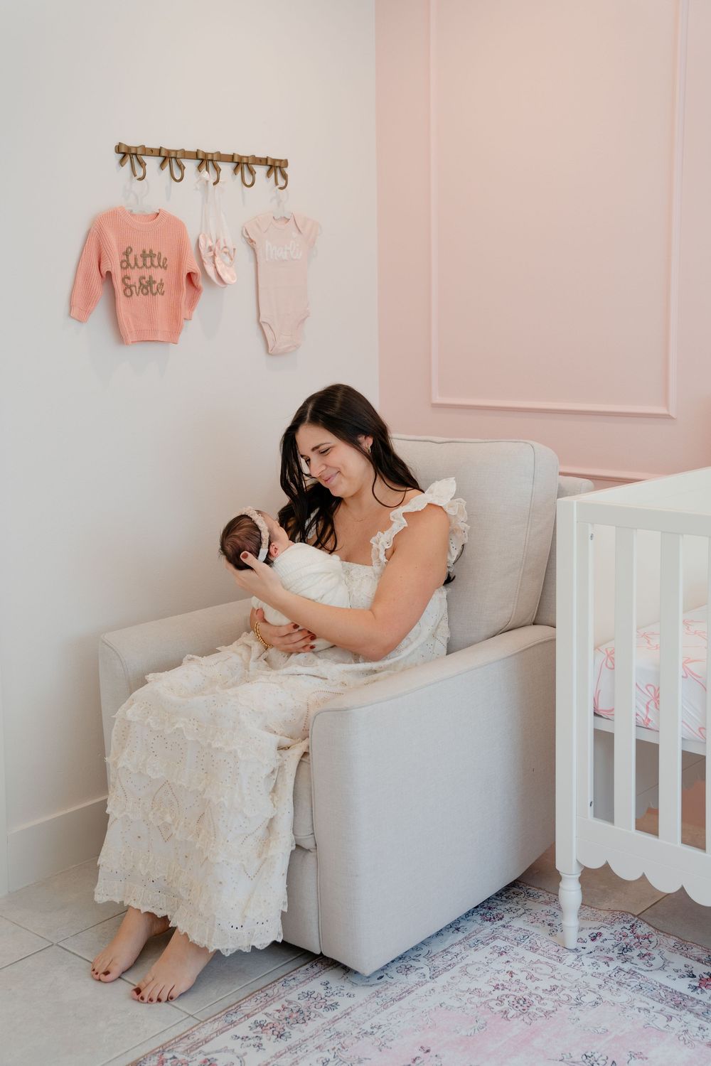 Nursery room decorated in soft pink tones with white crib and plush rug.