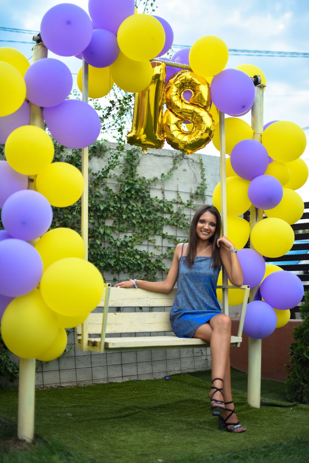 Outdoor party scene with yellow and purple balloon decorations on a sunny day.