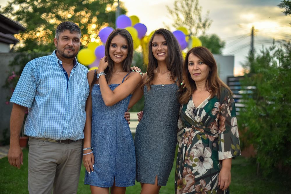 A group of people pose together outdoors at sunset with yellow balloons visible in the background.