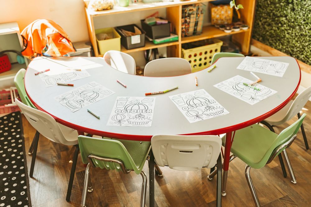 A collection of round cafe tables with green chairs arranged in a bright restaurant setting.