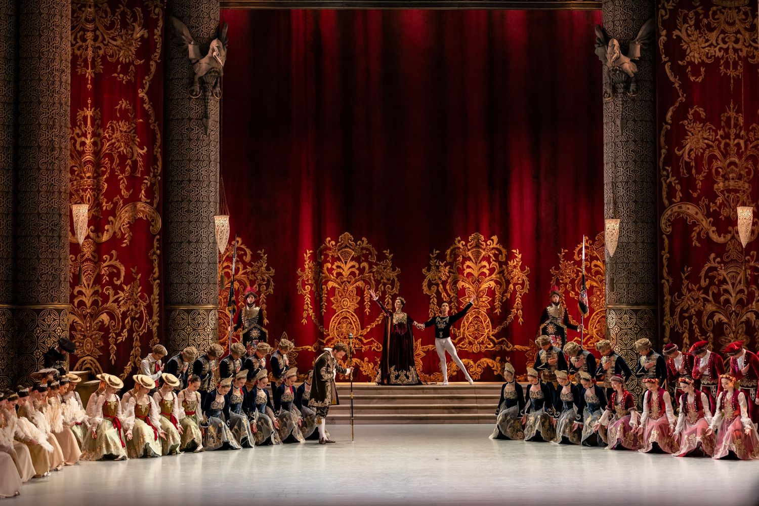 Grand Swan Lake ballet scene with ornate red and gold theatrical stage design.