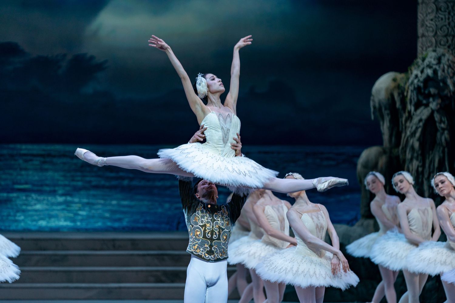Two ballet dancers perform Swan Lake pas de deux in white tutus on stage.