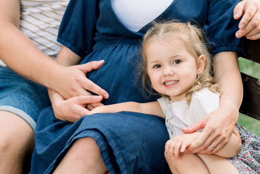 A close-up view of a family sitting together on a park bench.