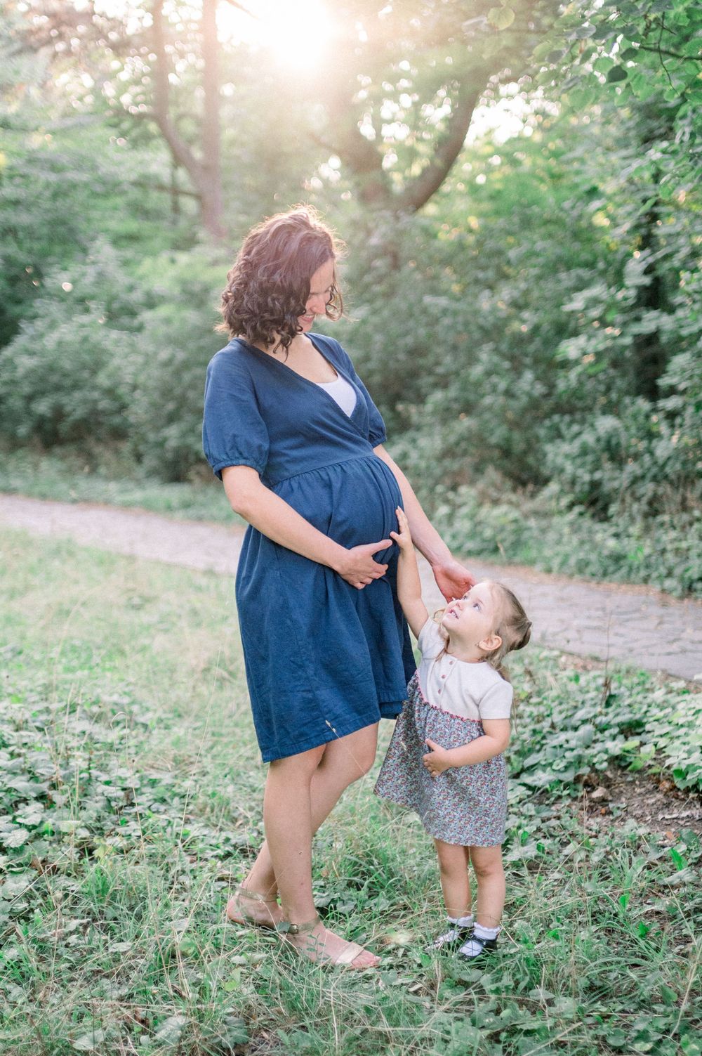 Sweet interaction between adult and small child on a nature path surrounded by greenery.