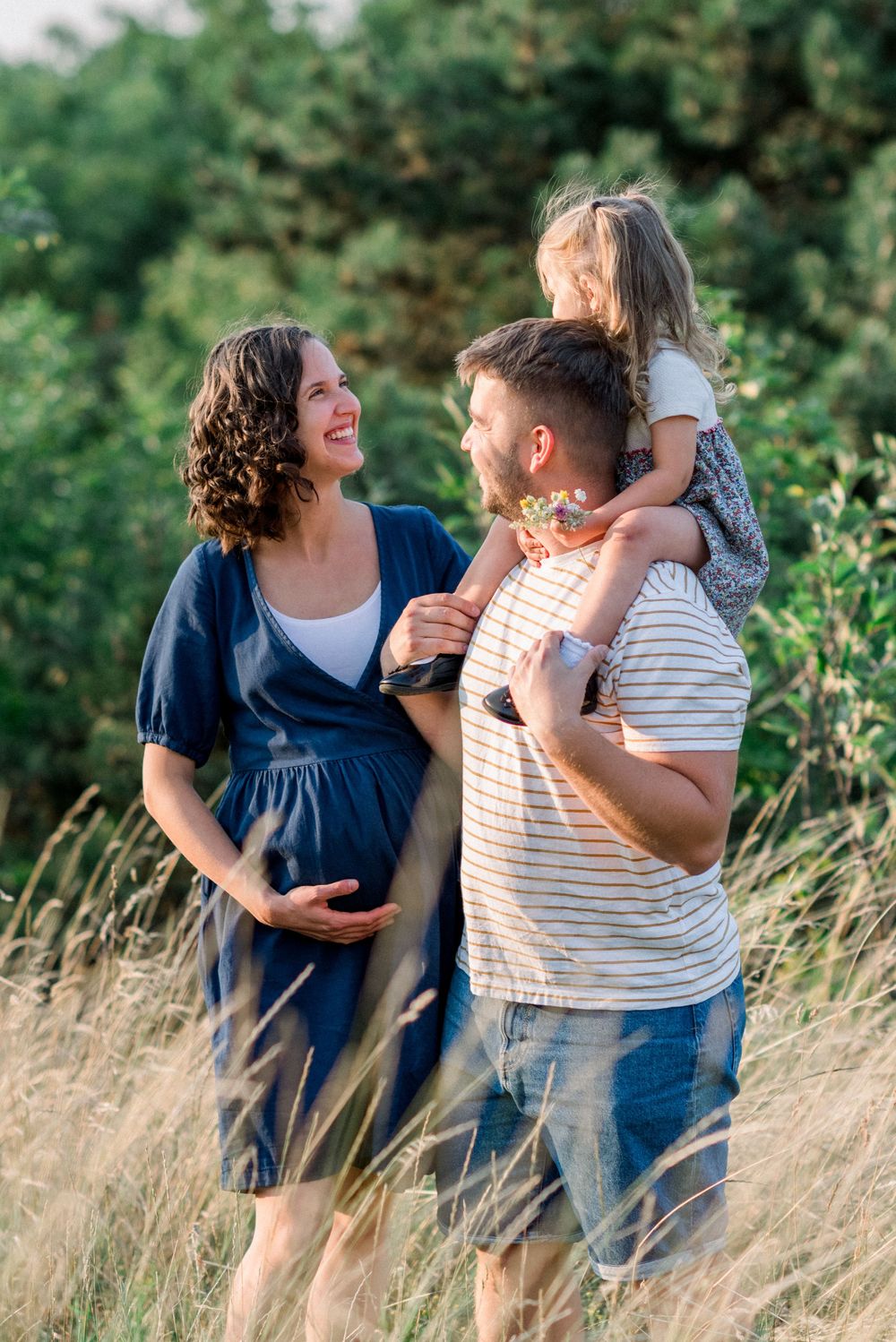 Family sharing joyful moments together in a sunlit field with tall grass.