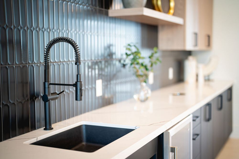 Modern kitchen with black faucet, white countertop, and blue tile backsplash features stylish minimalist design.