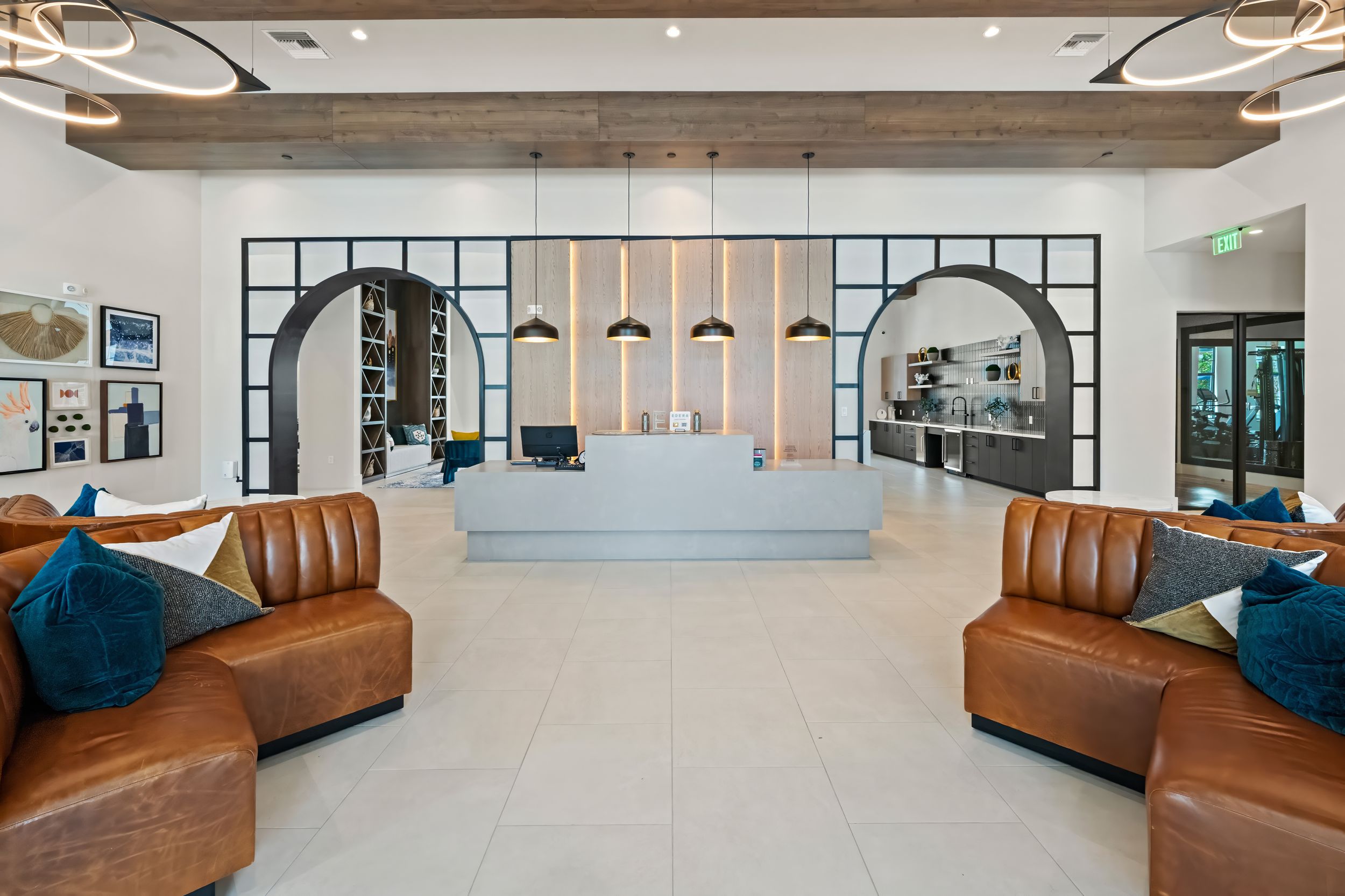 Modern office lobby with curved brown leather sofas, blue pillows and arched doorways leading to bright interior spaces.