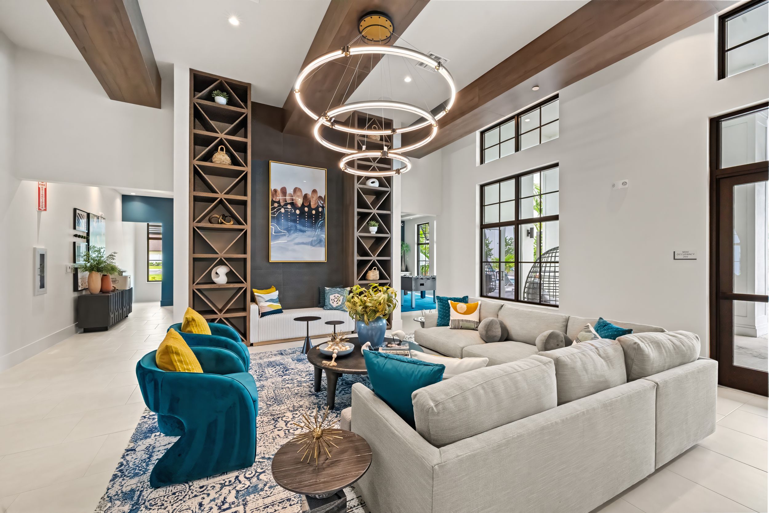 Modern living room with turquoise accent chairs, white sectional, circular chandelier and custom built-in wine storage.