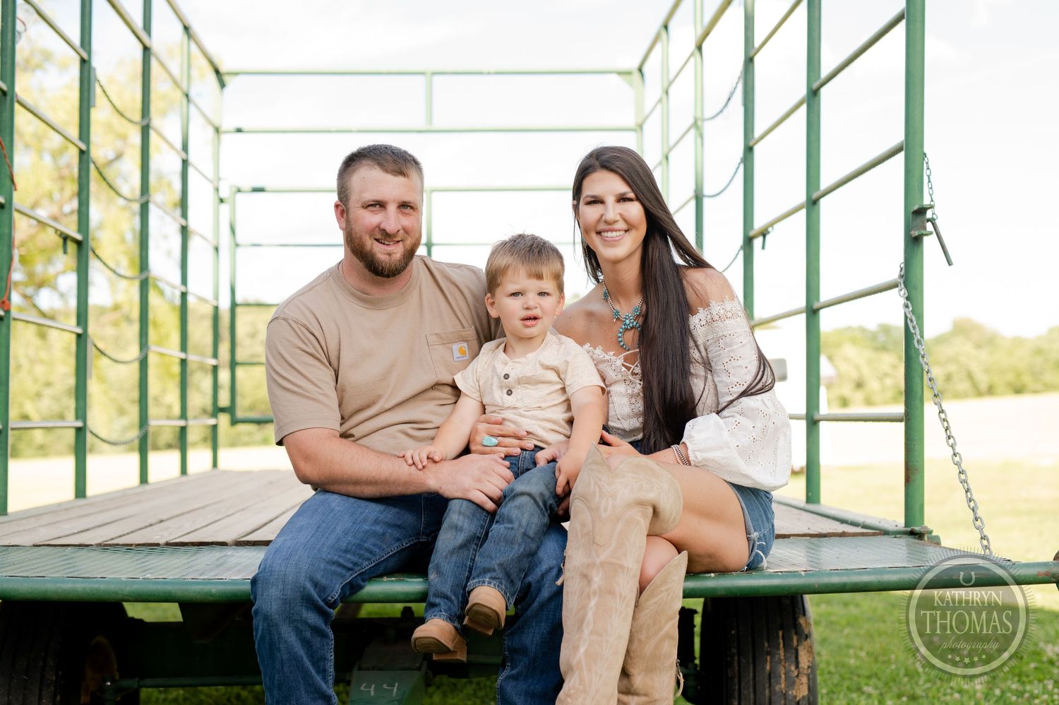 Family sitting together on green metal platform outdoors.
