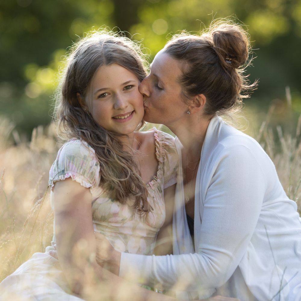 Two people share intimate moments in tall grass during golden hour.