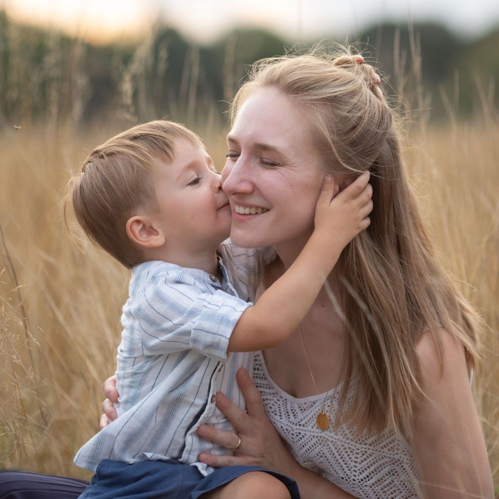 Mother and child share tender moments in golden field during sunset.