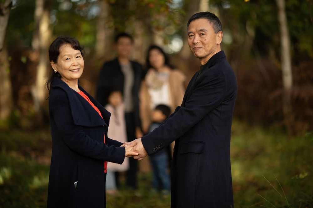 Couple shares intimate moments during outdoor photo session in wooded area.