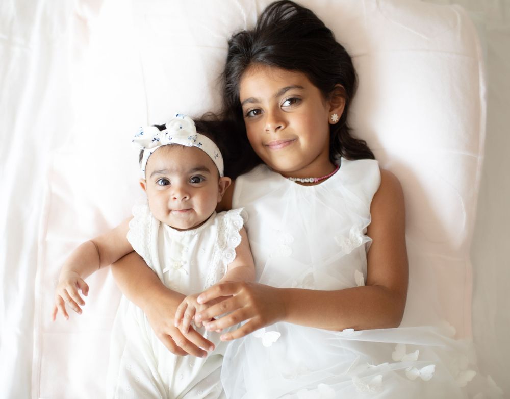 Children cuddle together on white background in studio setting.