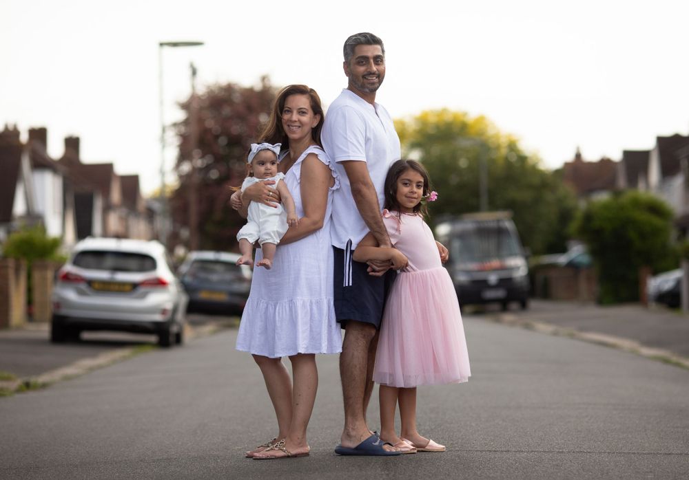 Family members stand together on suburban street in white and pink outfits.