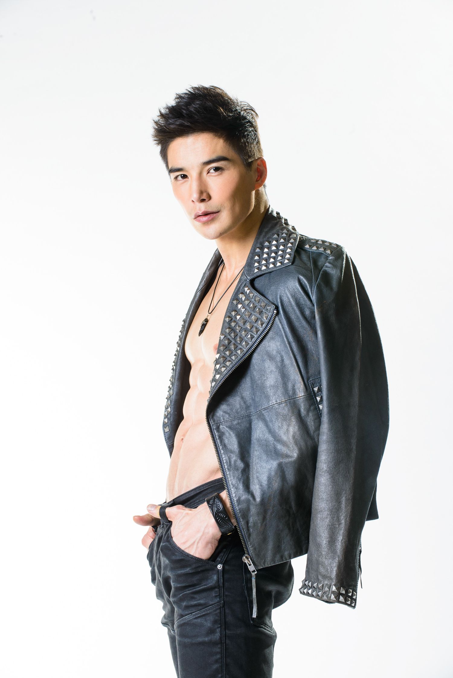 Fashion model wearing studded leather jacket poses against white background.