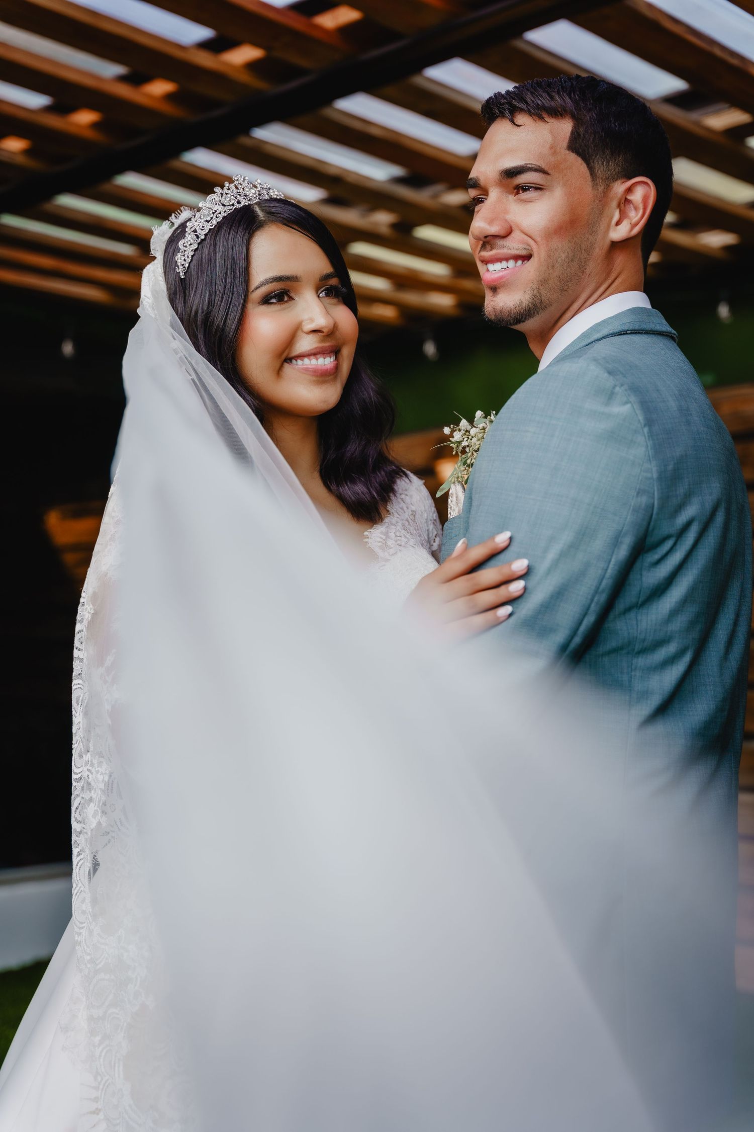 A joyful newlywed couple share a romantic moment under wooden beams at their wedding ceremony.