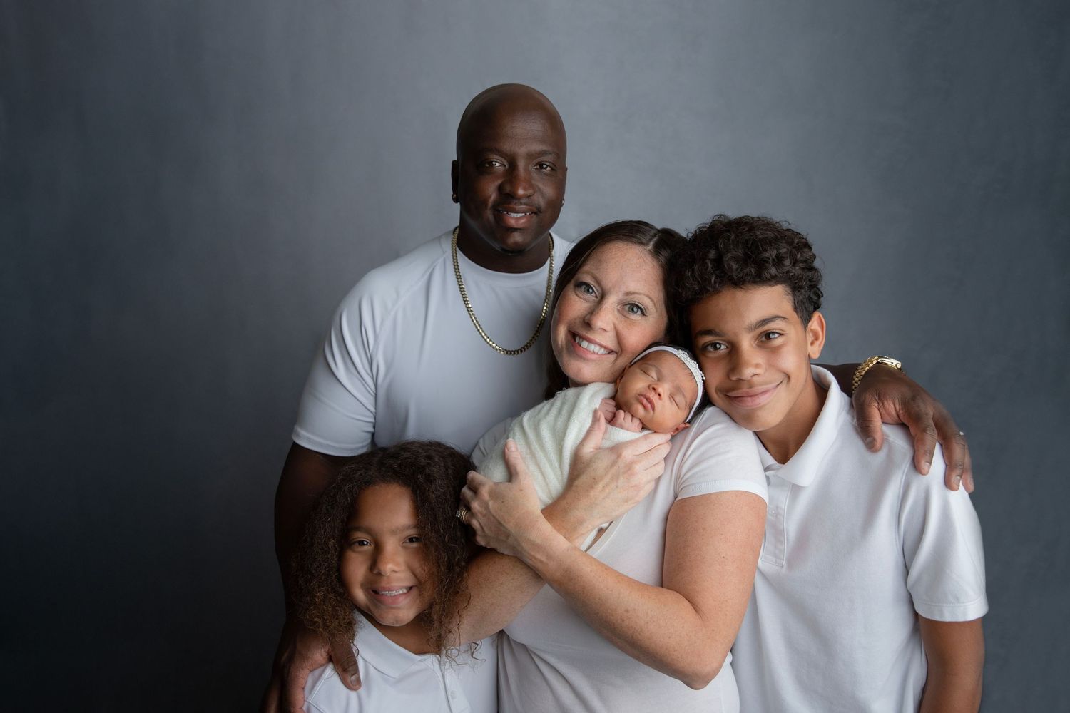 Multiracial smiling Family portrait with newborn baby during Central Florida photography session.