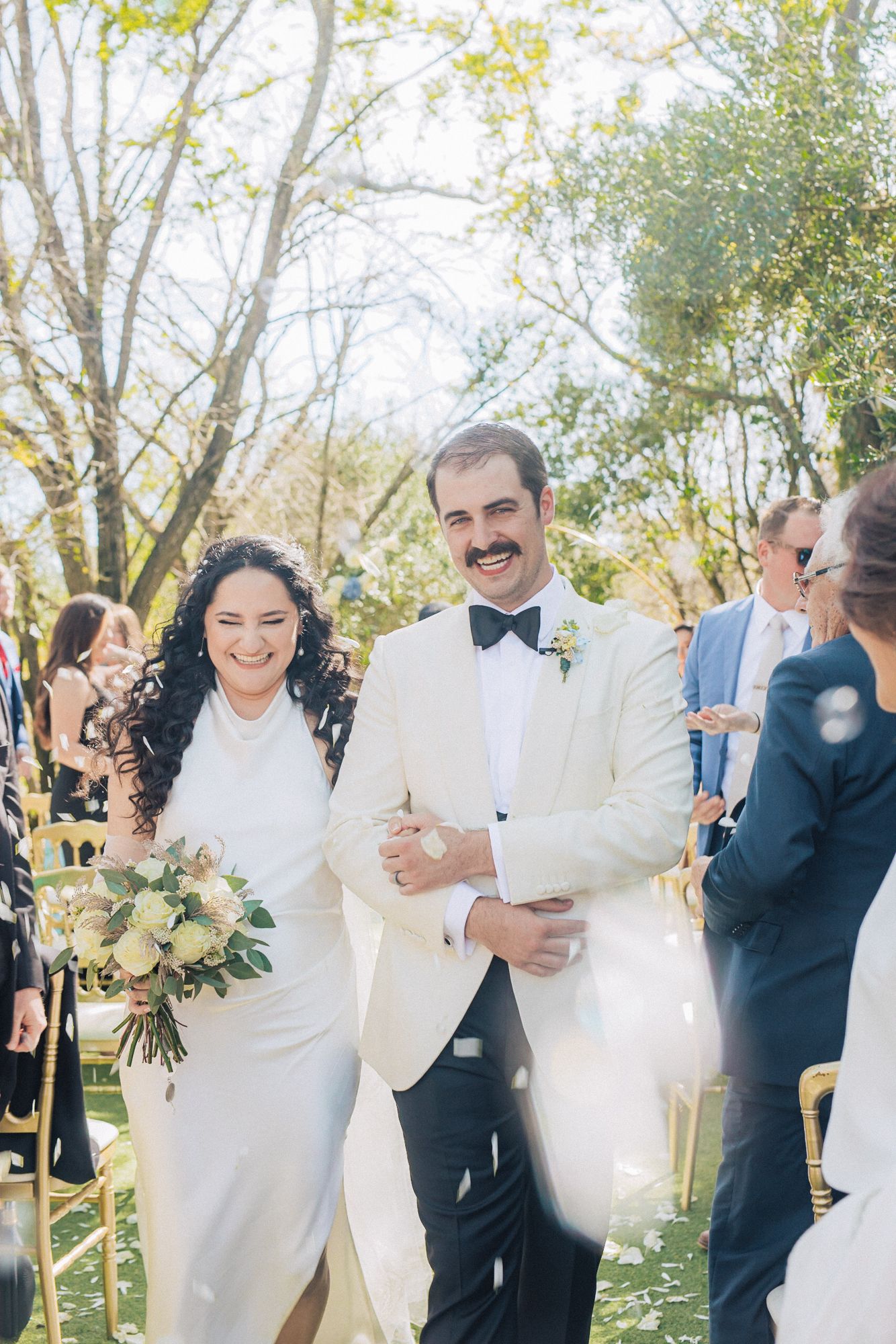 A joyous outdoor wedding ceremony with the newlyweds walking down the aisle in white attire amid greenery and guests at Quinta do torneiro.