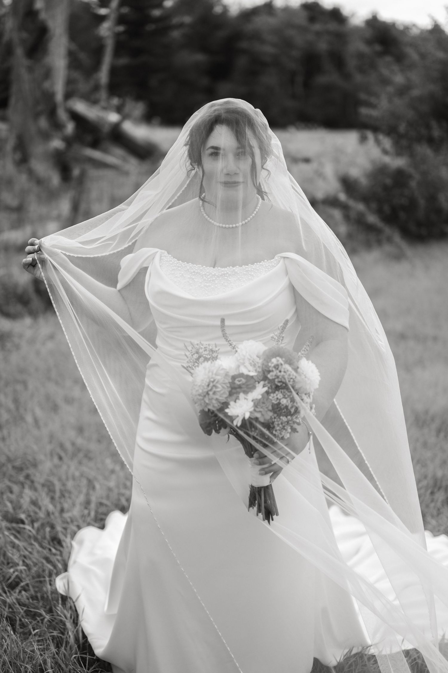 A vintage black and white photograph showing a couple in wedding attire with flowing veil creating a dreamy effect.