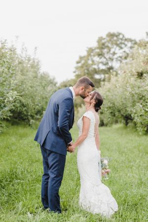 Romantic wedding couple shares a tender moment in a lush garden setting with greenery and soft lighting.