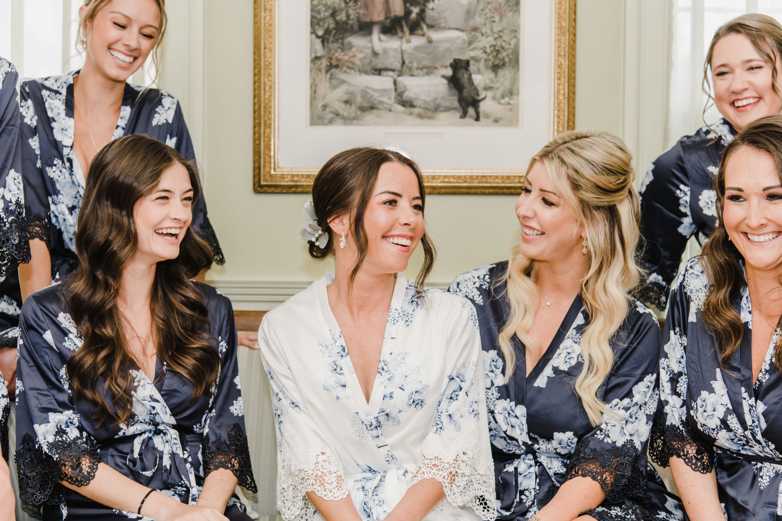 A group in matching floral robes sharing a joyful moment while getting ready for a wedding celebration.
