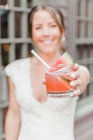 A refreshing watermelon cocktail garnished with lime and watermelon slice served in a rocks glass with a straw.