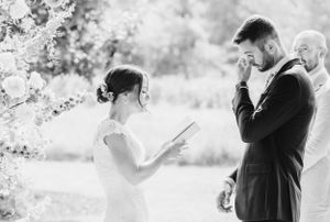 Black and white photo showing a tender moment during an outdoor wedding ceremony as vows are being read.