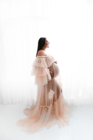 Ethereal maternity portrait in flowing peach-colored sheer gown.