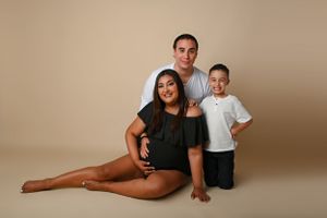 Studio portrait of family posing together against beige background.