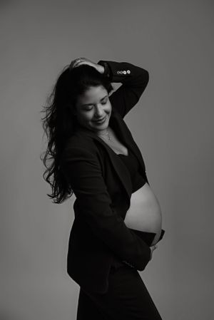 Black and white maternity portrait with woman in elegant black outfit.