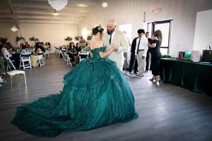 A person wearing a flowing emerald green ballgown twirls and dances gracefully across a studio floor. #QuinceneraPhotography #CarlsbadNM