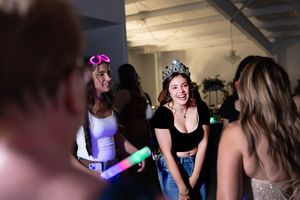 Partygoers dance and laugh while holding glow sticks at a nighttime celebration. #CarlsbadNM #QuinceneraPartyPhotography #QuinceneraDress