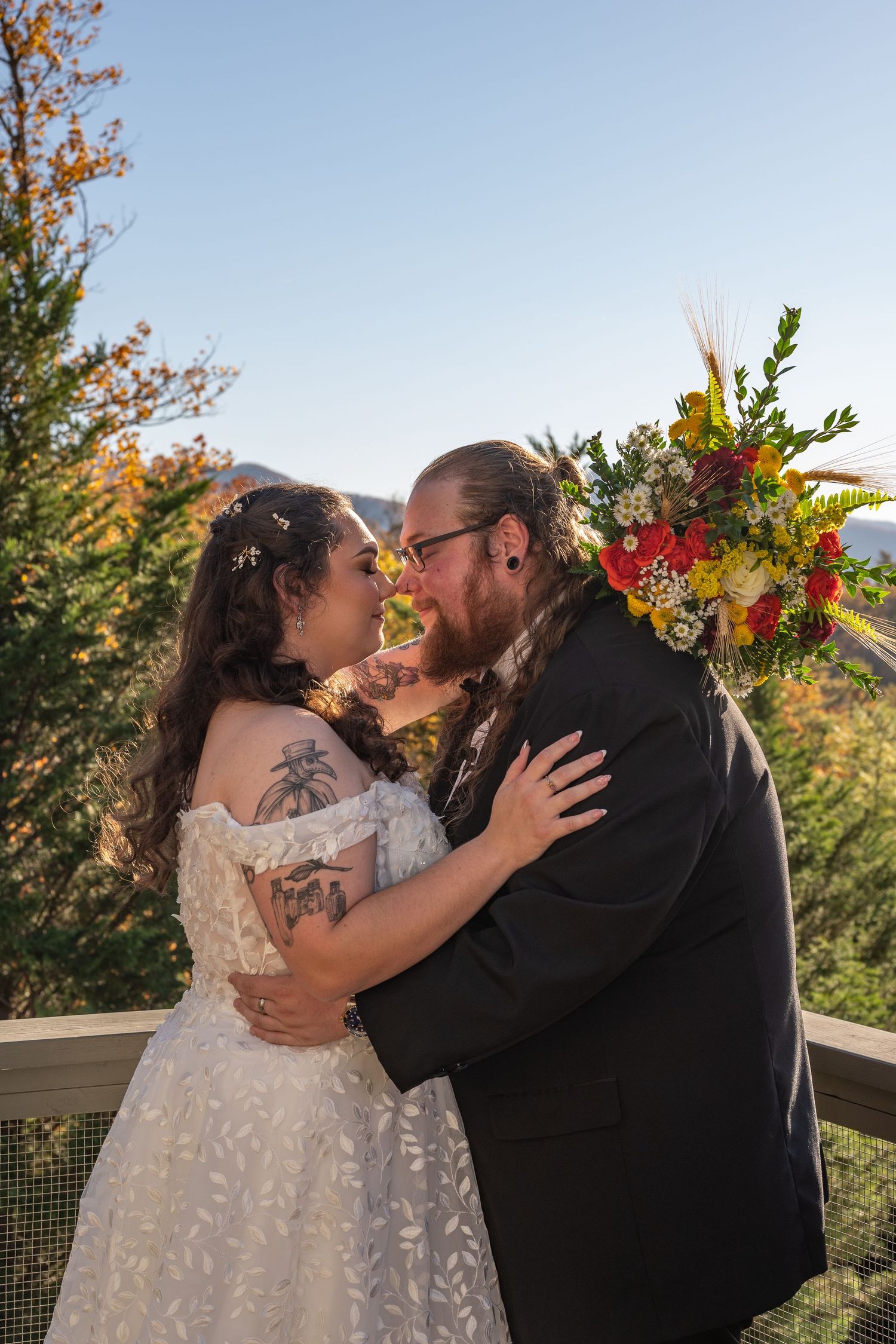 A tender moment between newlyweds with colorful floral arrangements and mountain views.