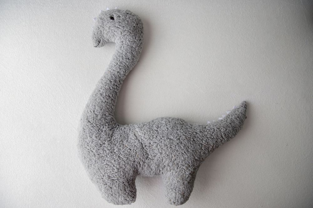 Gray fluffy brontosaurus dinosaur stuffed animal plush toy on white background.