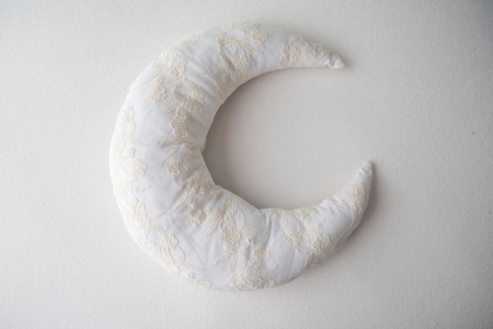 Handmade white crescent moon pillow with delicate floral fabric texture on a clean white background.