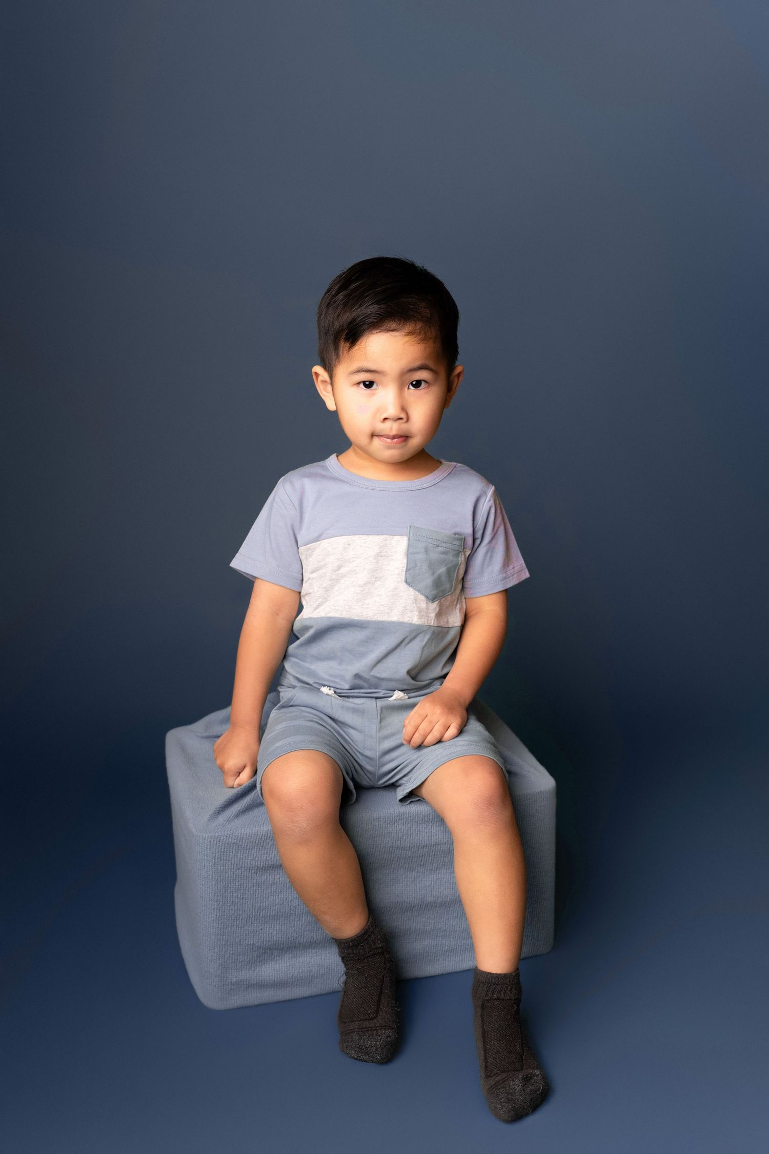 Playful studio portraits in grey attire against a navy blue background.