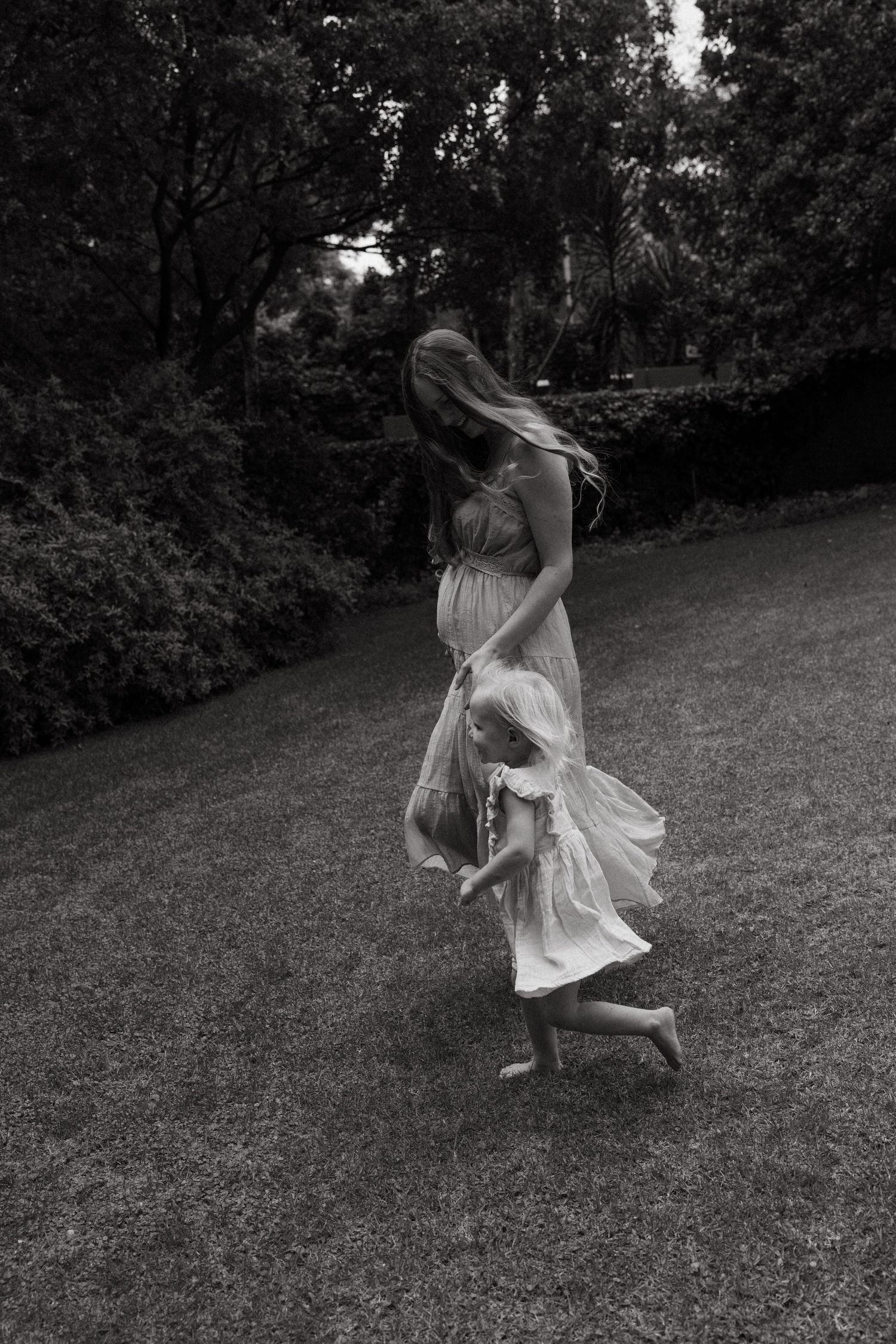 Dancing figures in light dresses create movement across a grassy hillside.