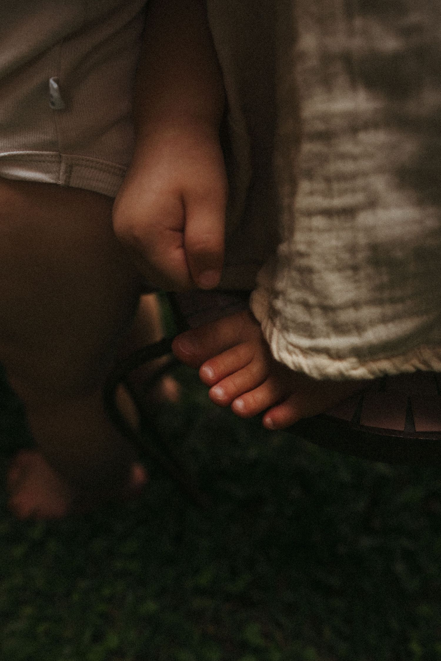 Close-up detail of bare feet on grass in warm evening light.