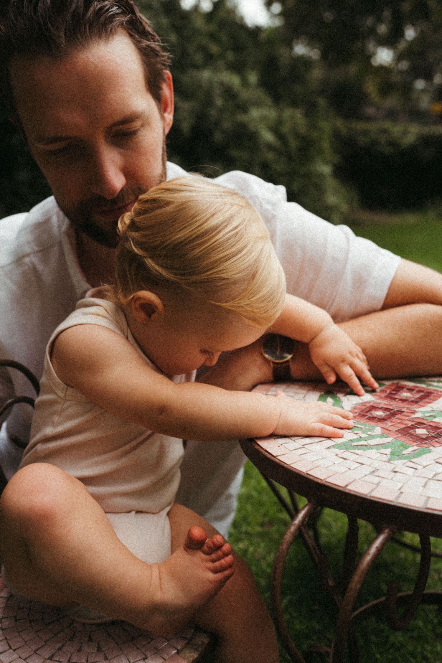 A quiet moment of reading together outdoors on a patterned blanket.