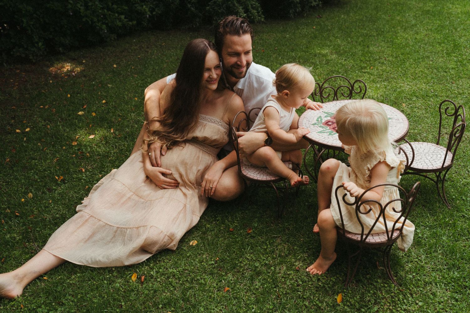 Family members relax together on grass while sharing a book outdoors.
