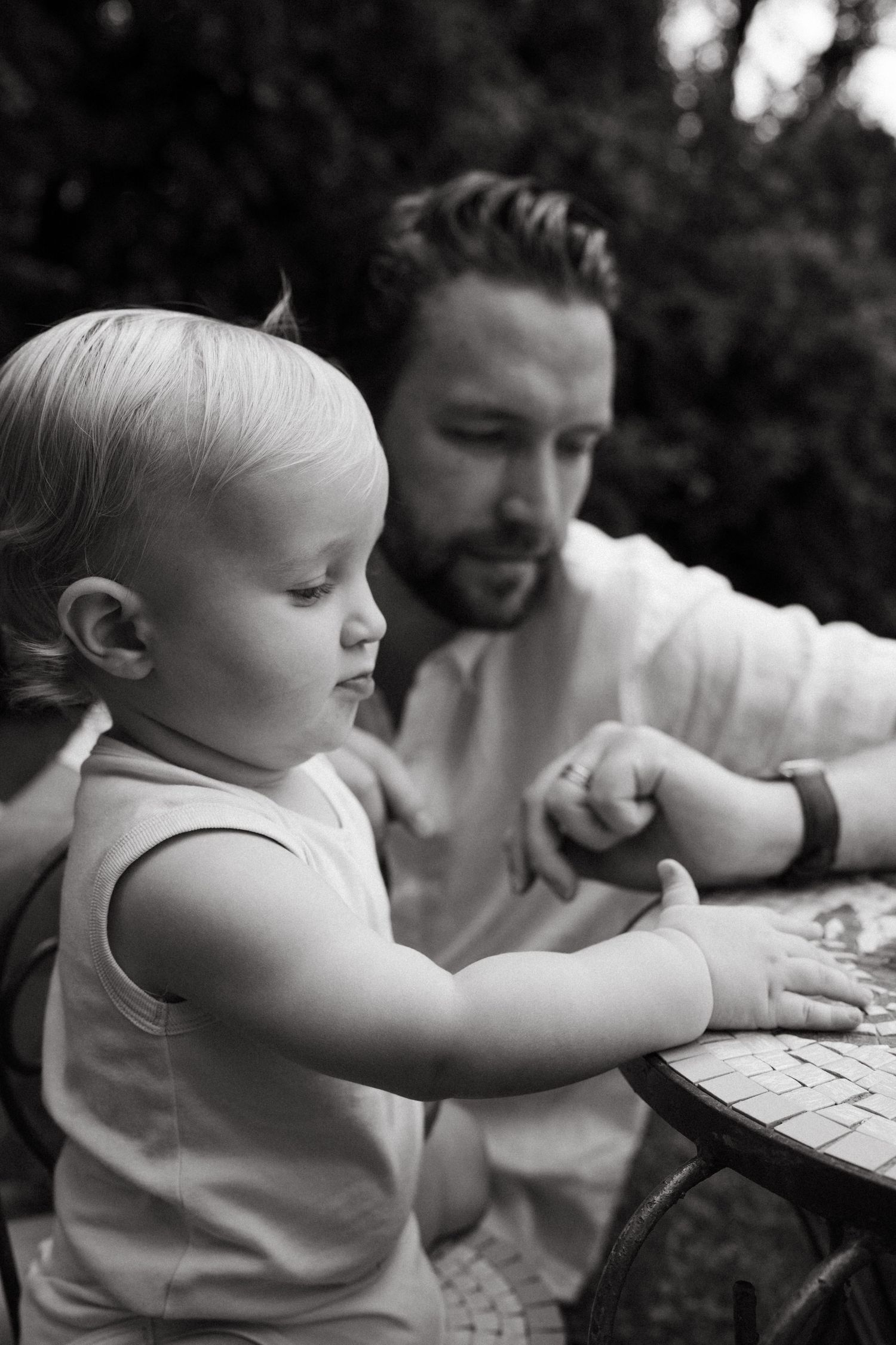 A close-up black and white series showing a small child reaching toward a keyboard.