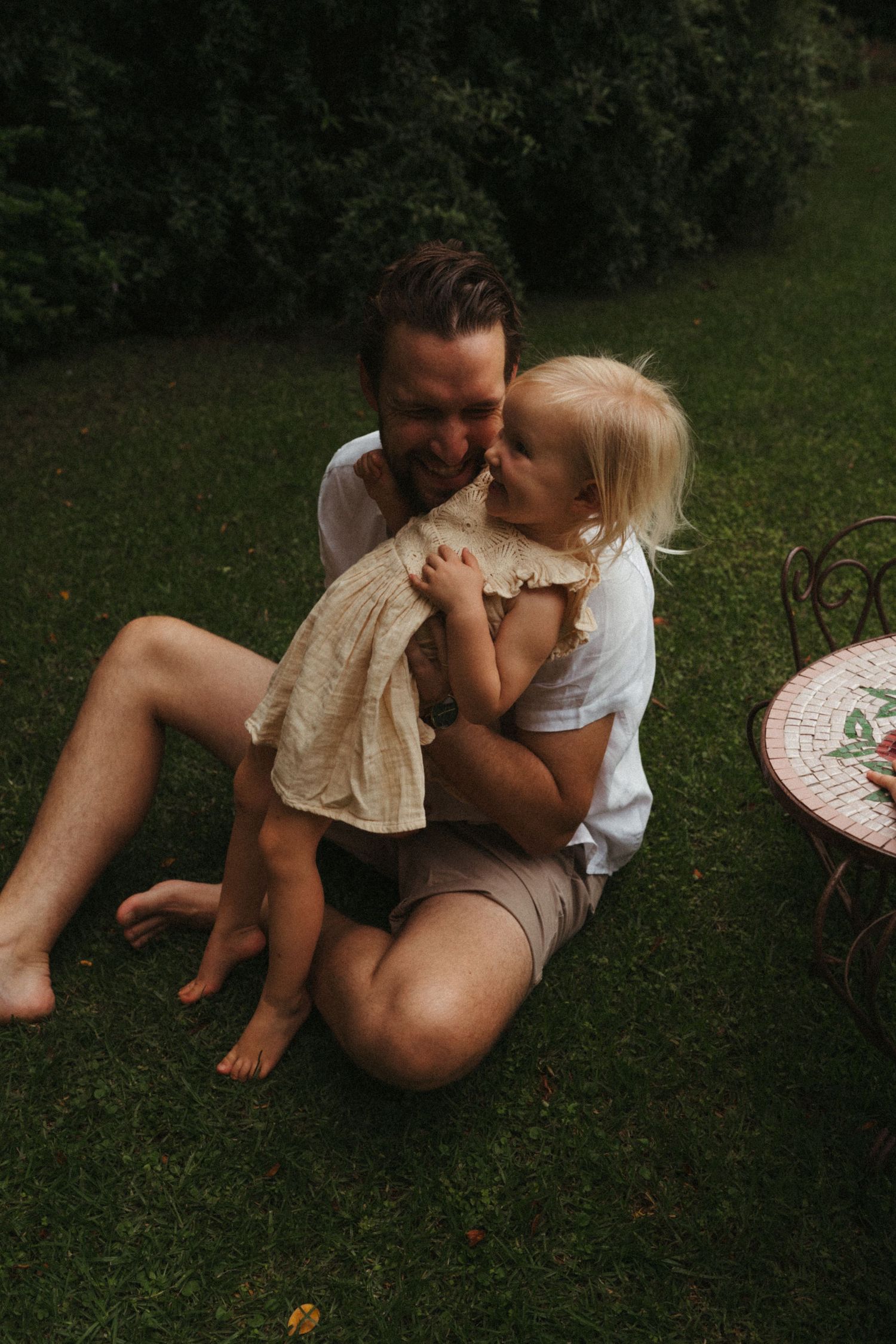 A tender moment captured between family members relaxing on green grass.