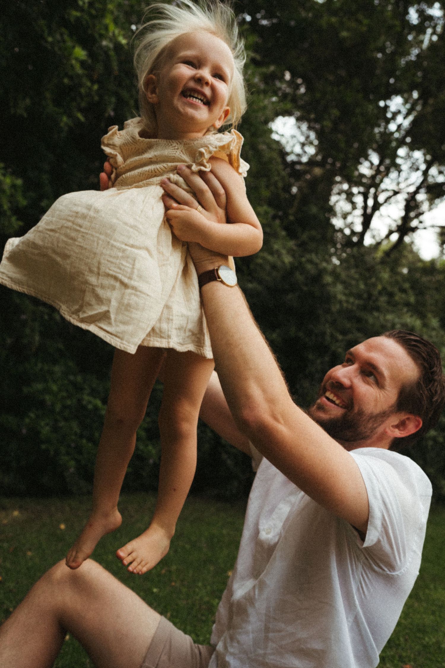 Happy moments of play and lifting captured in an outdoor setting.