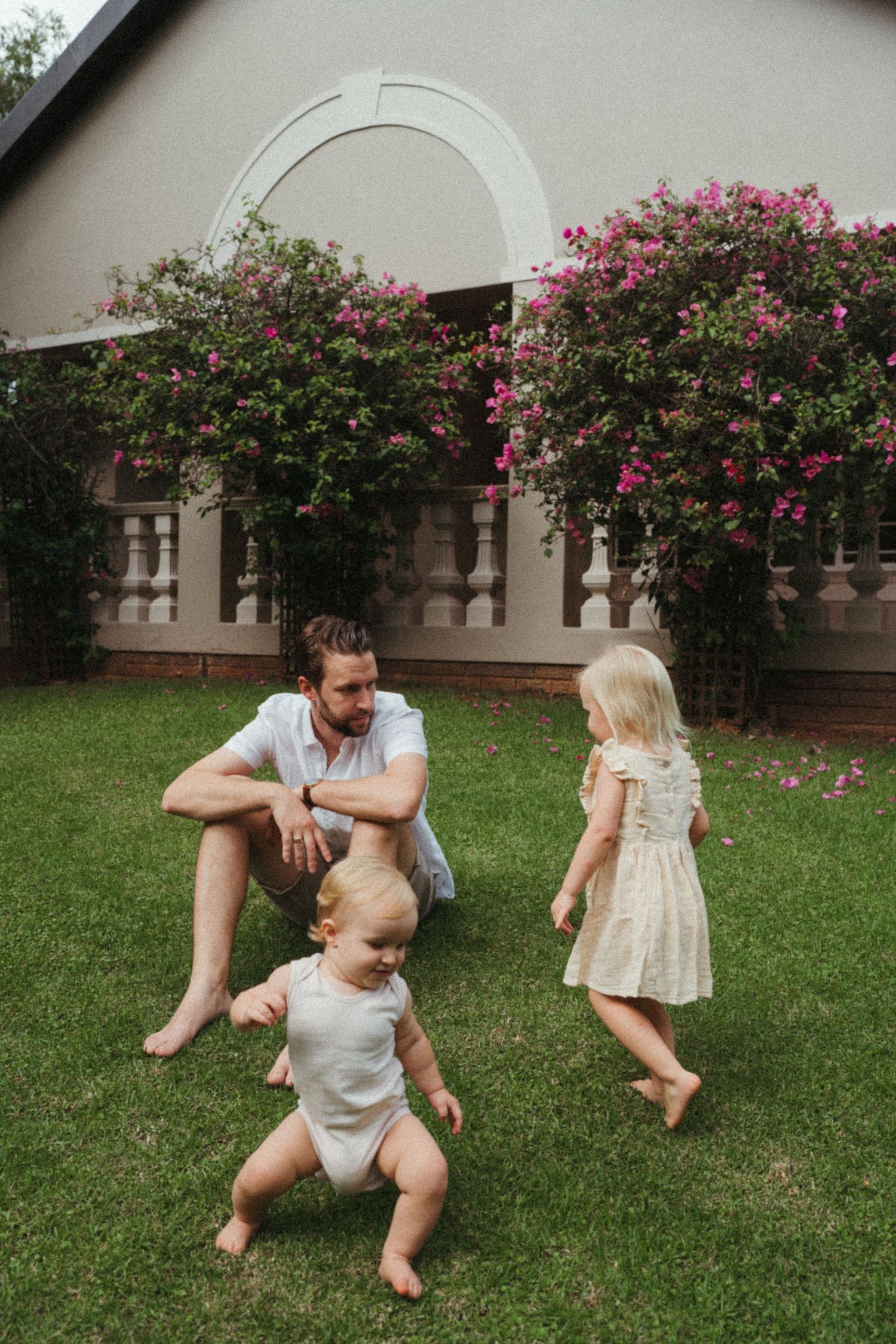 Family playtime captured in front of a house with blooming pink rose bushes.