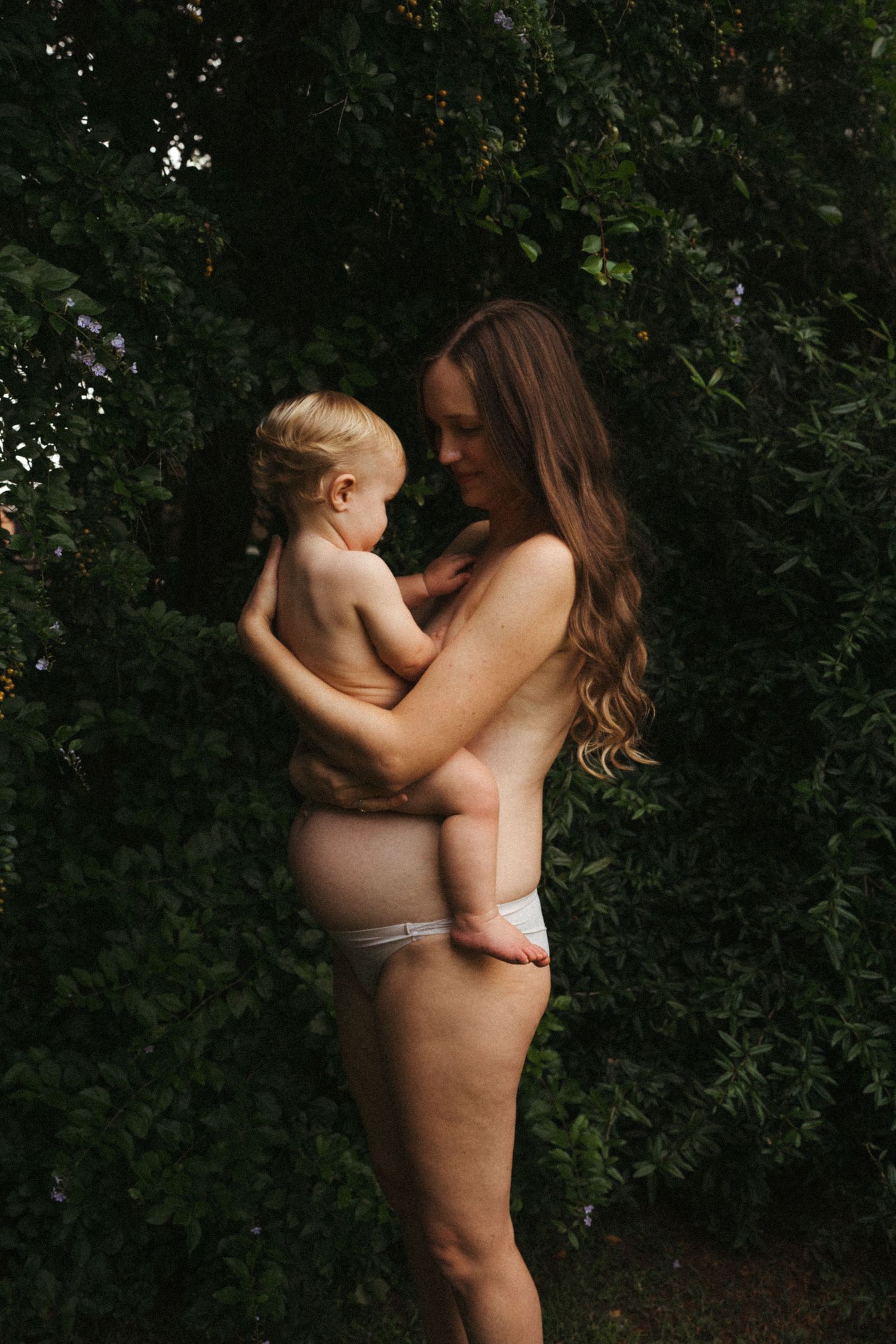 Tender moments captured in natural lighting against a leafy backdrop.