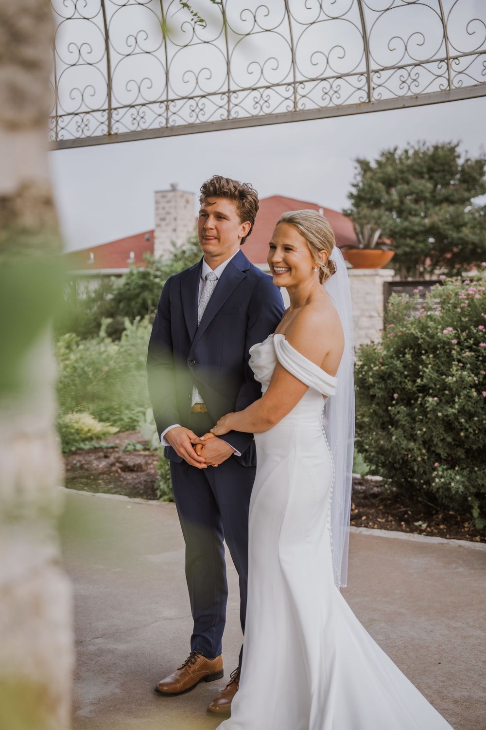 A couple shares an intimate first look moment in their wedding attire outside on a sunny day.