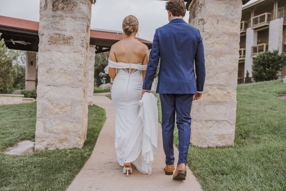 A couple walks together on a stone path during their wedding day.