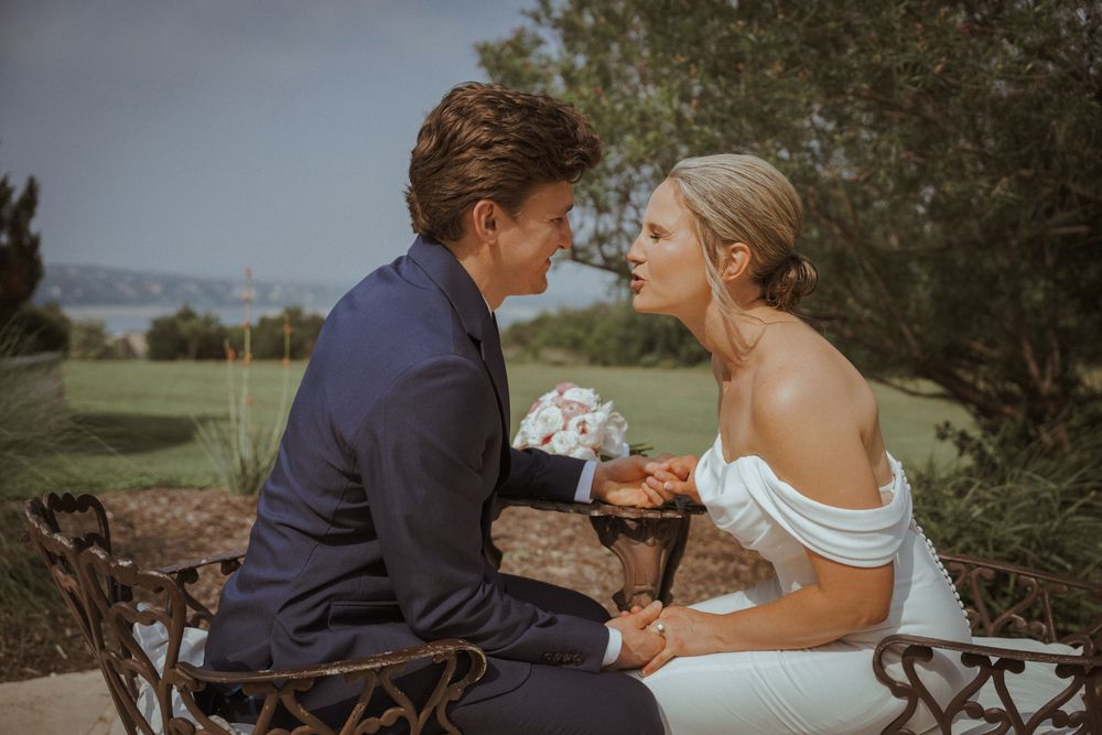 A couple shares an intimate moment on rustic metal chairs during their wedding.